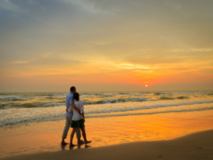 couple walk the beach at sunset